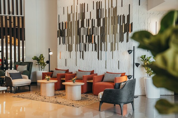 A modern lobby with a seating area, a decorative wall, and a potted plant. - Voila Bagatelle (Moka)
