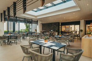 A spacious indoor dining area with high ceilings, natural light from skylights, and a variety of seating arrangements.