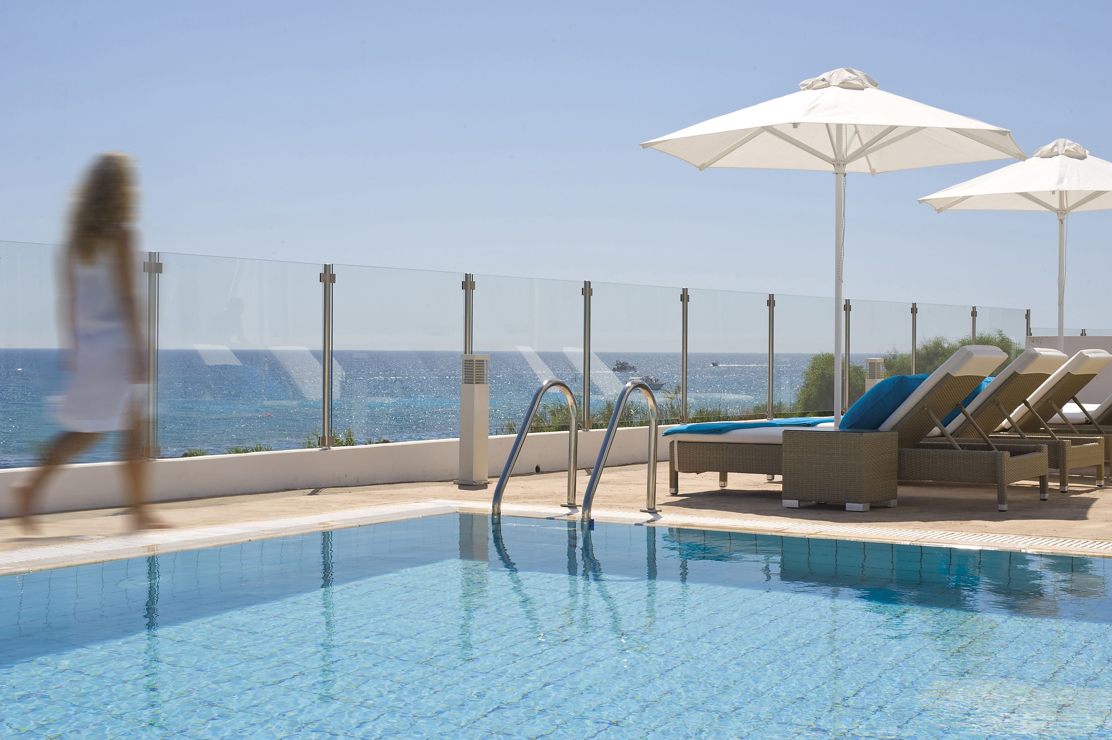 A pool area with lounge chairs and umbrellas, overlooking a body of water.