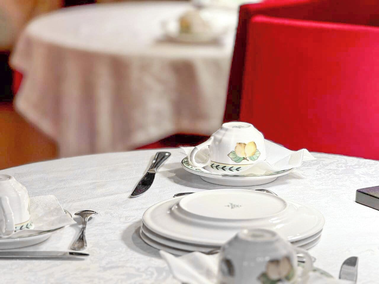 A table set for dining with white tablecloths, silverware, and a teapot.