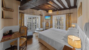 Een hotelkamer met een groot bed, een bureau met stoel, een televisie en een raam met gordijnen.