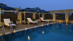 Un espace aménagé au bord de la piscine, avec des chaises longues et des parasols.
