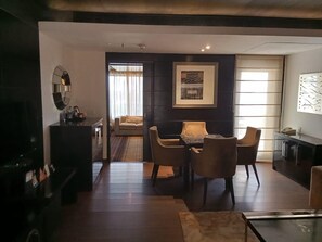 A modern living room with a dining area, a sofa, and a TV.