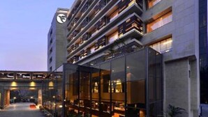Un hôtel moderne à plusieurs étages, doté d’une façade en verre et d’une tour horloge.