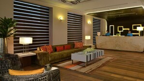 Un hall d’hôtel moderne avec un comptoir d’accueil, des canapés et une table basse.