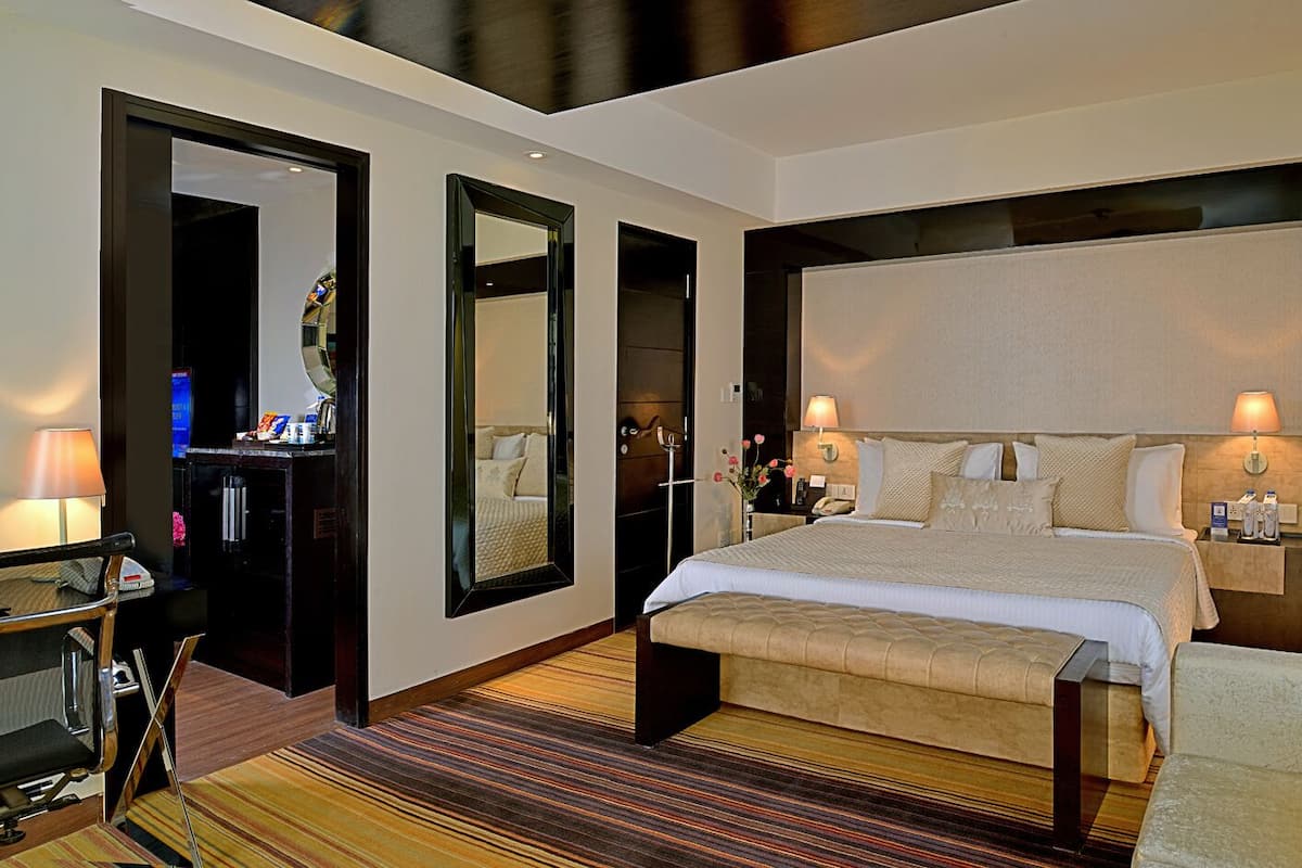 Ein modernes Hotelzimmer mit einem großen Bett, Nachttischen, einem Schreibtisch und einem Spiegel.