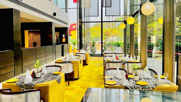 Un restaurant moderne avec des tables et des chaises jaunes, de grandes fenêtres et un intérieur lumineux.