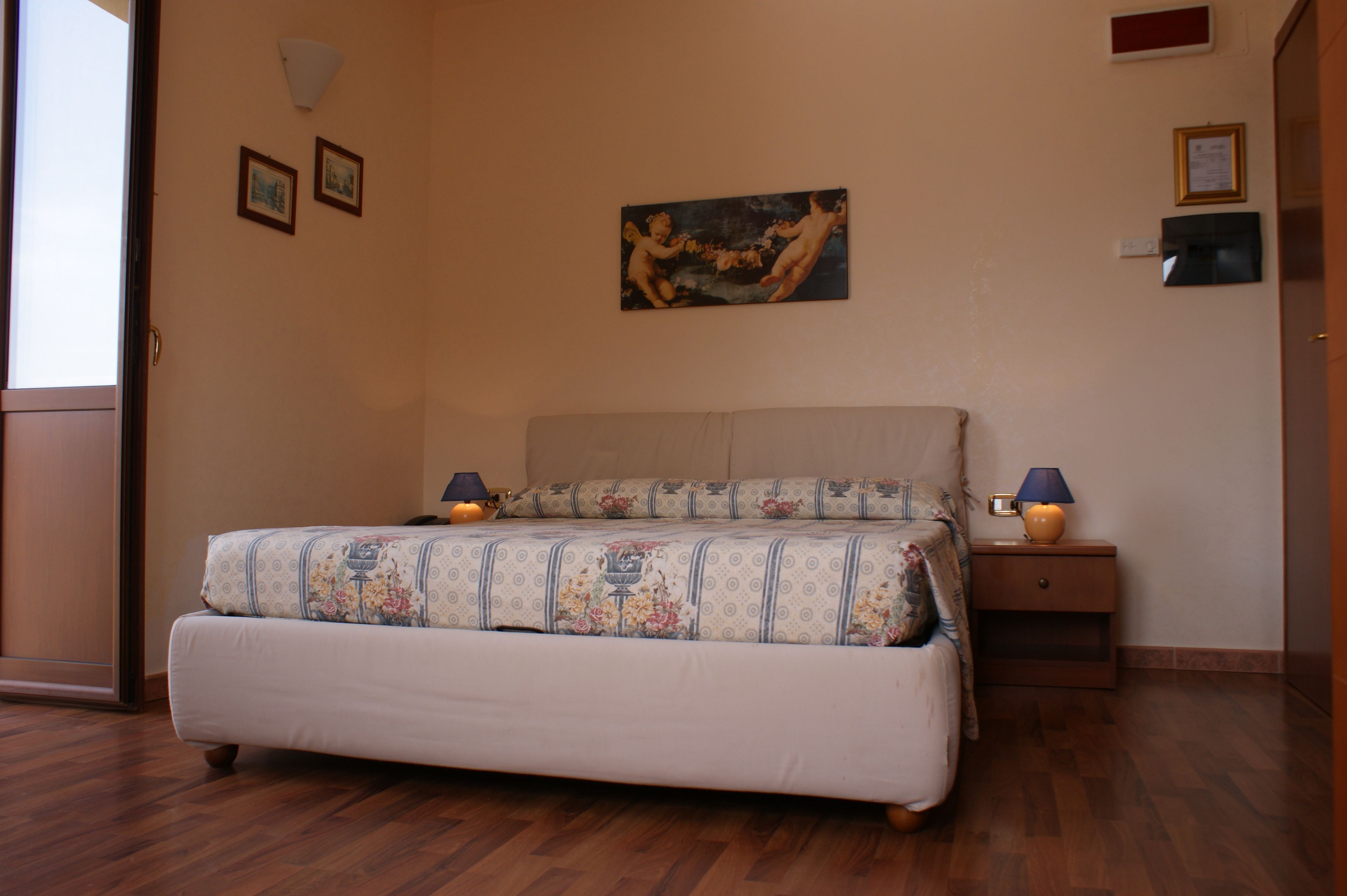 Una camera da letto con un letto, comodini, un quadro appeso al muro e una porta.