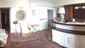 Un salón amplio con una silla de madera, una mesita pequeña y un tapete decorativo.