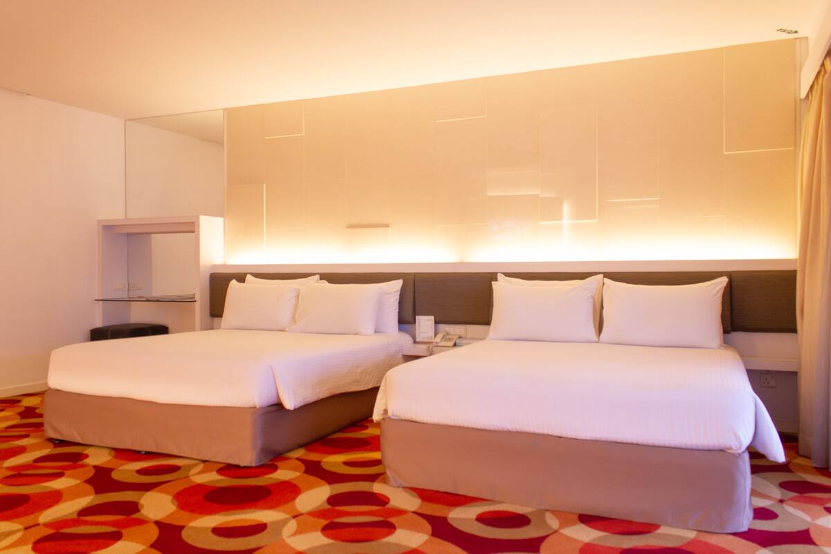 A hotel room with two beds, a large mirror, and a red patterned carpet.