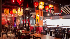 A restaurant with tables and chairs, red lanterns, and a counter. - The 5 Elements Hotel (Kuala Lumpur)