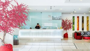 A reception desk with a large sign reading "5 ELEMENTS" and a receptionist behind it. There are two potted plants with pink flowers on either side of the desk. - The 5 Elements Hotel (Kuala Lumpur)