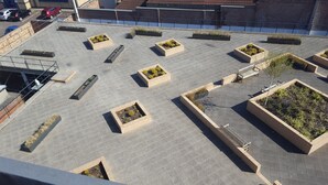 A rooftop terrace with multiple rectangular planters containing various plants, a few benches, and a visible staircase leading down. - Beaverbank Place - Campus Accommodation (Edinburgh)