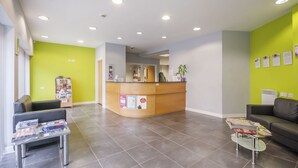 A reception area with a counter, seating, magazines, and a green wall. - Beaverbank Place - Campus Accommodation (Edinburgh)