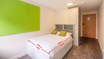 A bedroom with a bed measuring 120cm by 190cm, a green accent wall, and a wooden floor.