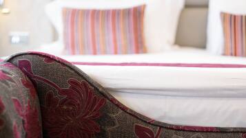 Una cama con sábanas blancas y almohadas a rayas.