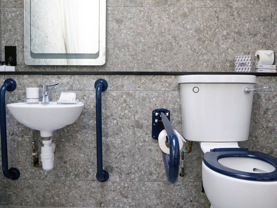 Une salle de bain équipée d’un lavabo, de toilettes et de barres d’appui.