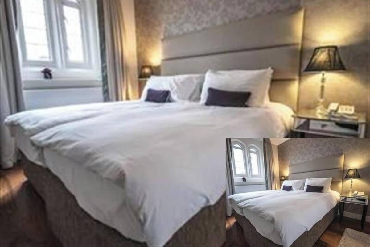 A hotel room with a large bed, a nightstand, a lamp, and a view of the outdoors.