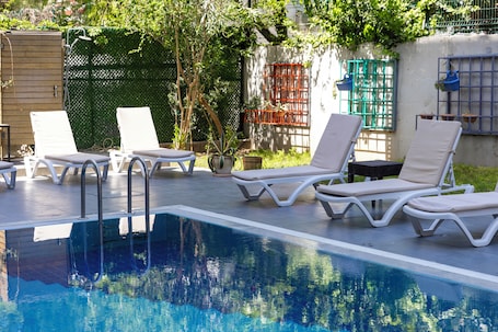 Una piscina al aire libre, sillones reclinables de piscina