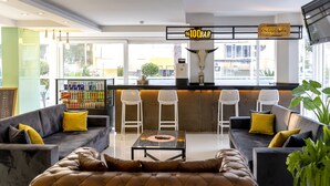 En moderne hotellobby med barområde, siddepladser og et stort vindue med udsigt til det fri.