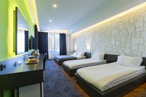 A hotel room with two beds, a desk with a chair, a large mirror, and a stone-textured wall. - Mene City Hotel (Antalya)