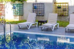 Una piscina con sillas de descanso y plantas en macetas.