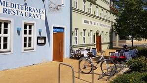 A Mediterranean restaurant and a hotel with outdoor seating and bicycles. - Hotel zum Weissen Ross (Delitzsch)