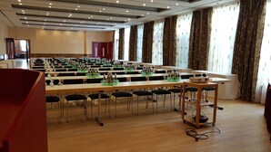 A conference room with long tables, chairs, and a podium. - Hotel zum Weissen Ross (Delitzsch)