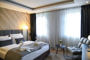 A modern hotel room with a large bed, a comfortable armchair, and a small table. - Hotel zum Weissen Ross (Delitzsch)