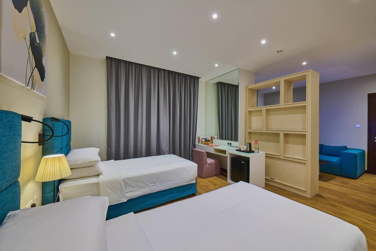 A hotel room with two beds, a desk, a chair, a wardrobe, and a mirror.