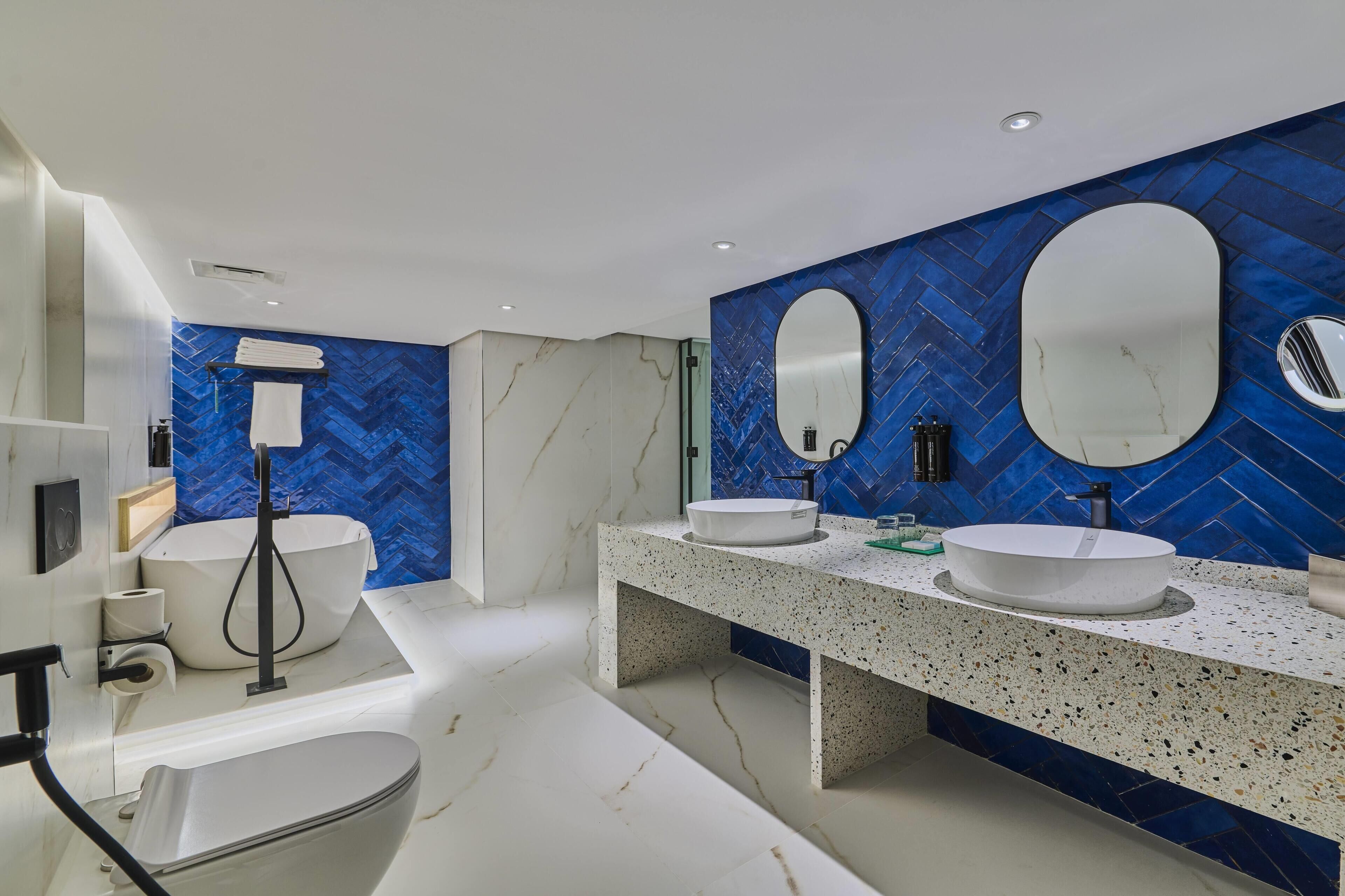 Une salle de bain moderne avec une baignoire sur pieds, deux vasques et un grand miroir.