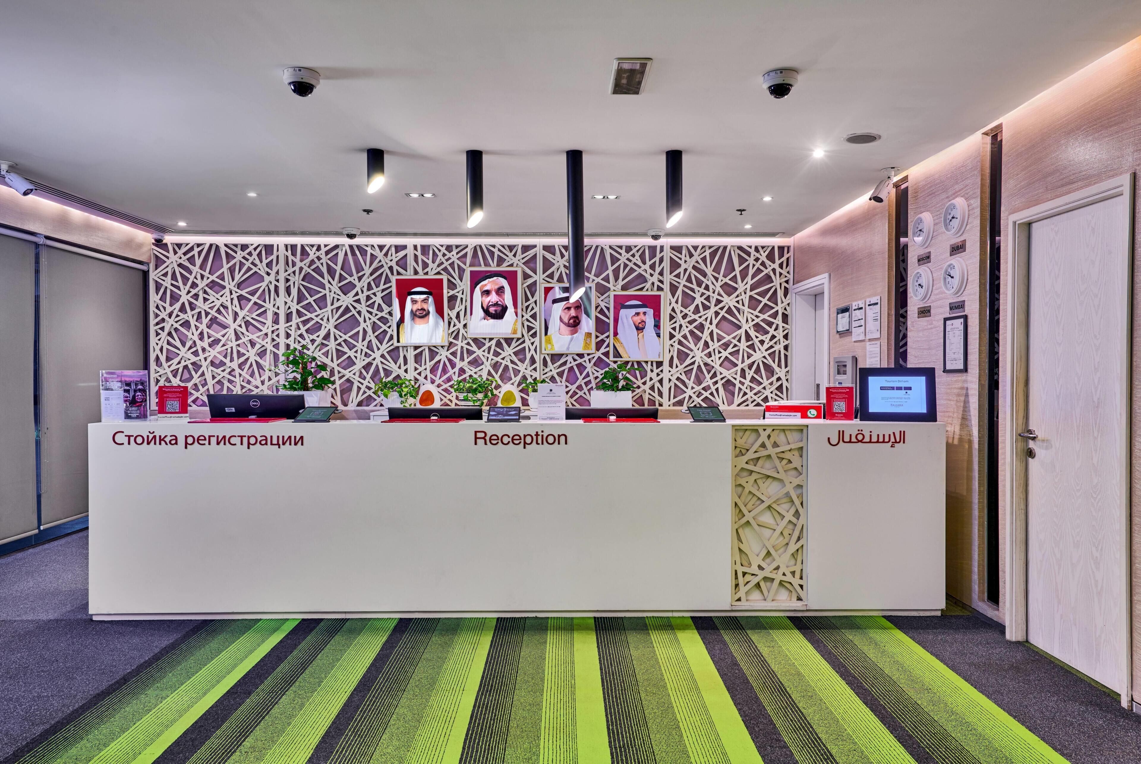 A reception desk with registration and reception areas, a patterned wall, and a green striped carpet.