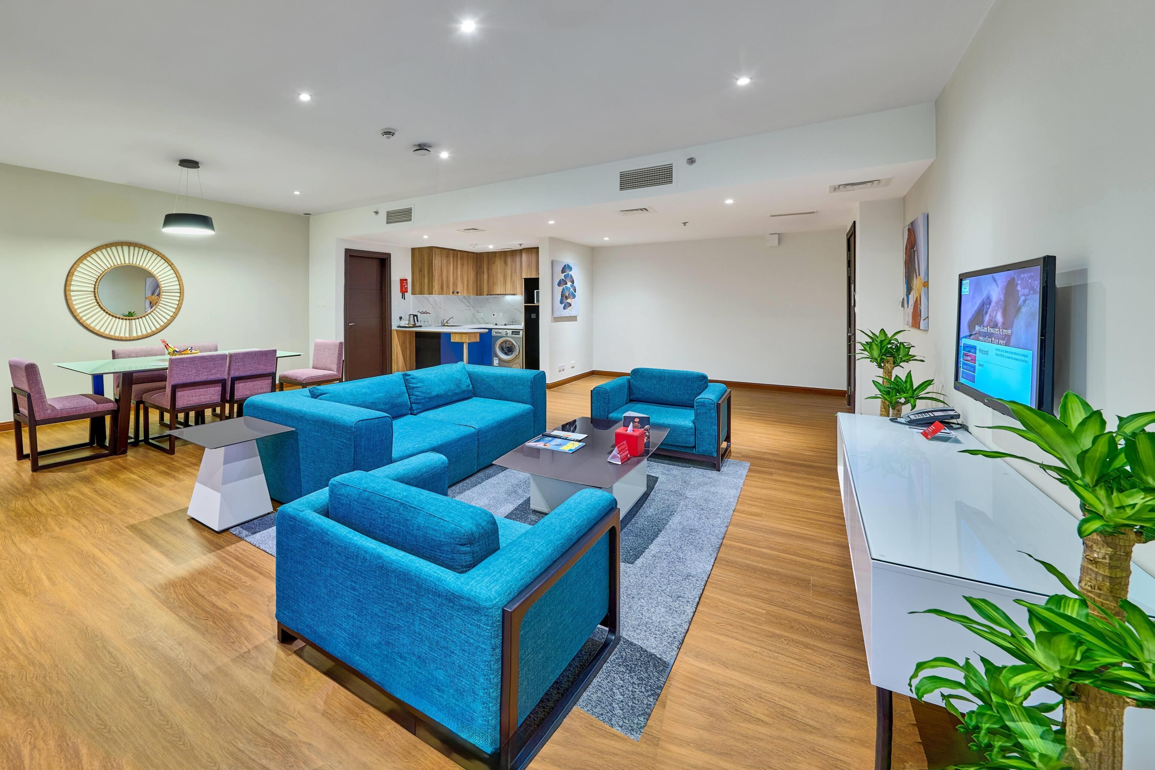 A modern living room with a sectional sofa, a coffee table, a TV, and a dining area with chairs and a table.