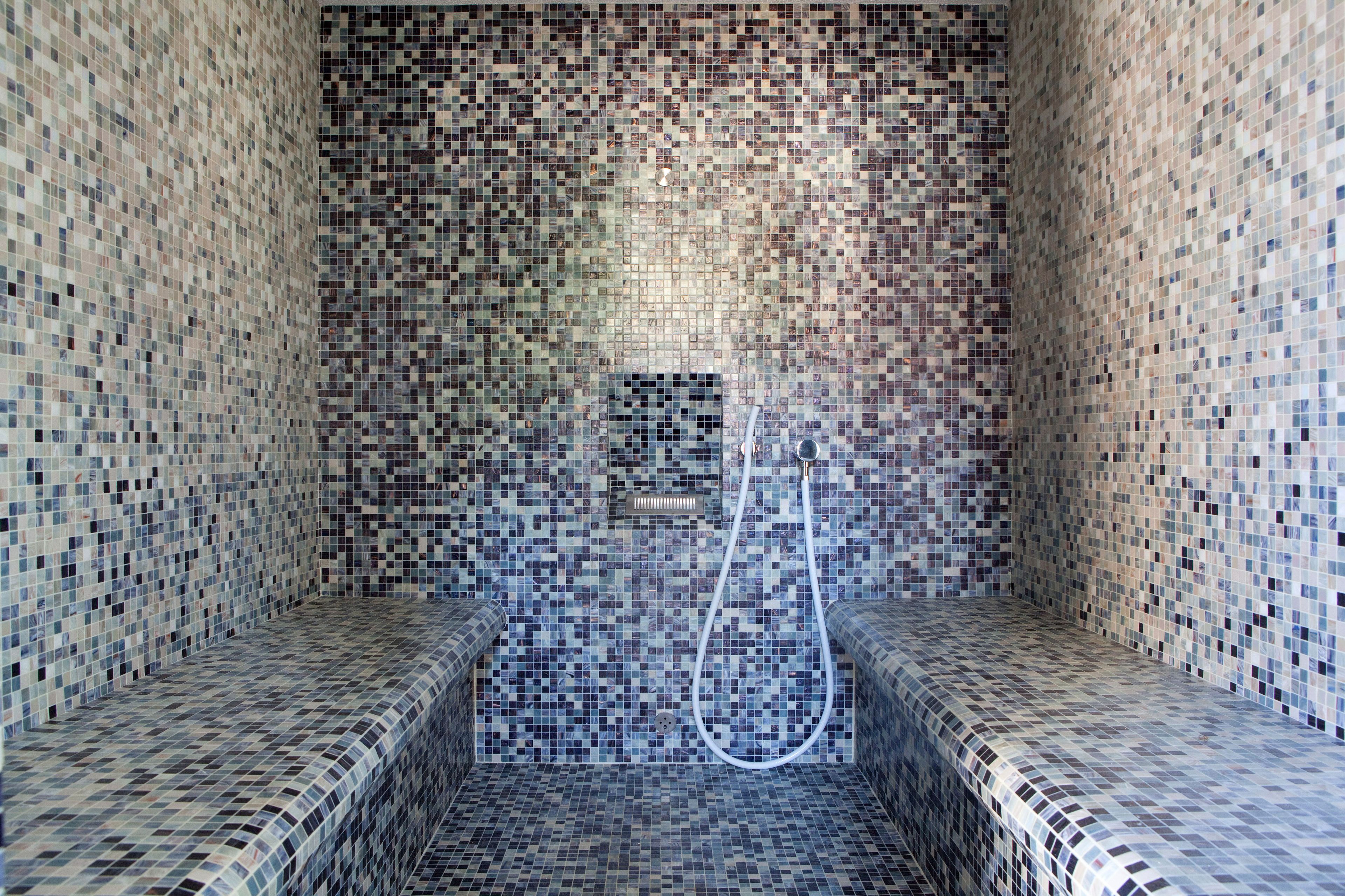 A small, tiled room with a bench and a shower area.