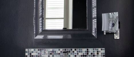 Un baño con un lavamanos blanco, un espejo y una ventana.