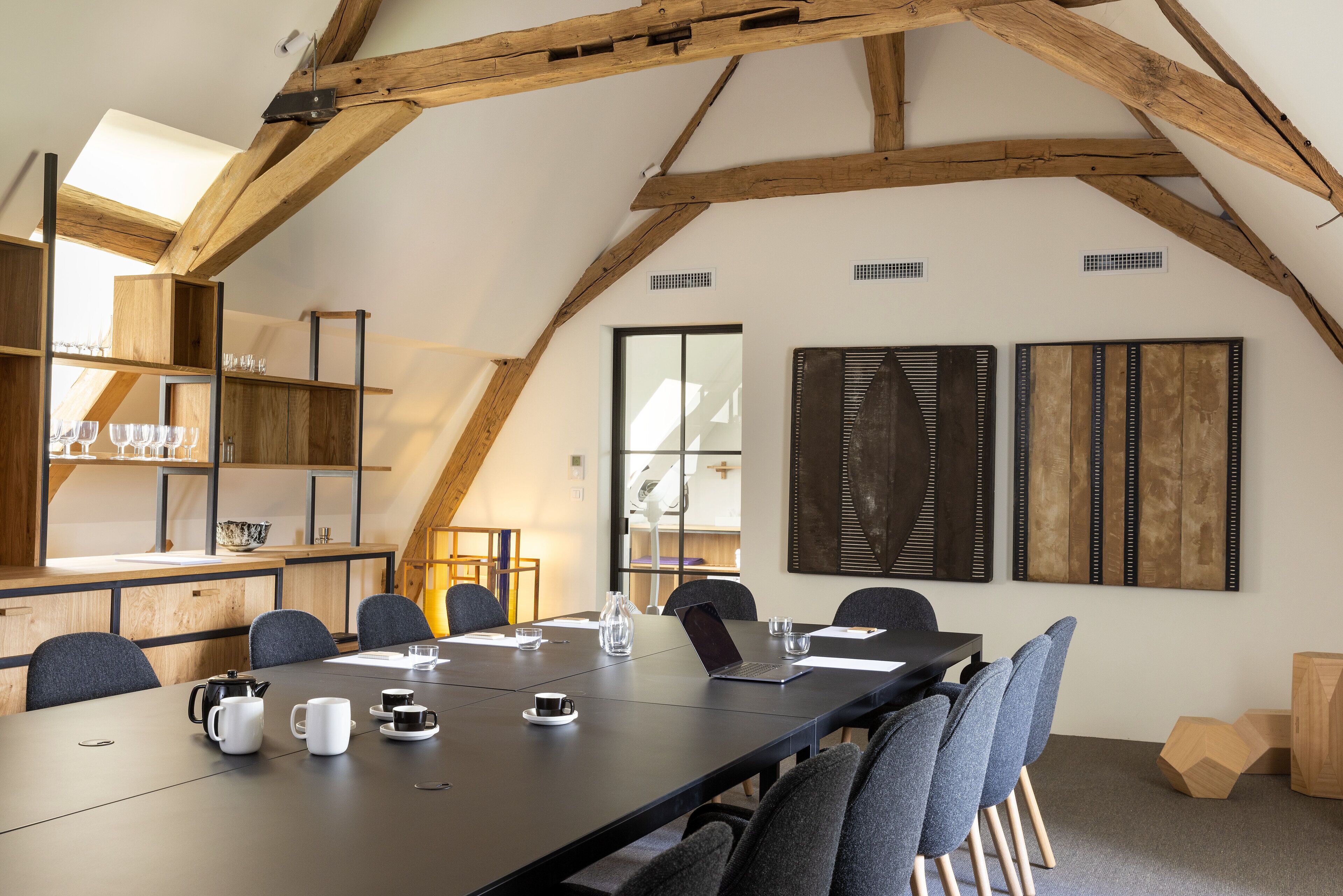 A conference room with a long table, chairs, and a coffee station.