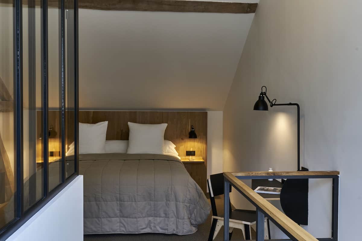 A bedroom with a bed, bedside lamps, a desk, and a chair.