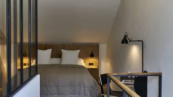 A bedroom with a bed, bedside lamps, a desk, and a chair.