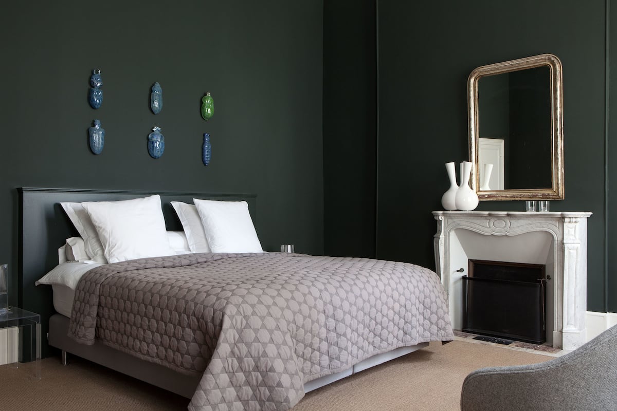 A bedroom with a bed, a fireplace, and wall-mounted vases.