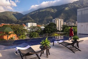 Una piscina al aire libre, sombrillas, sillones reclinables de piscina