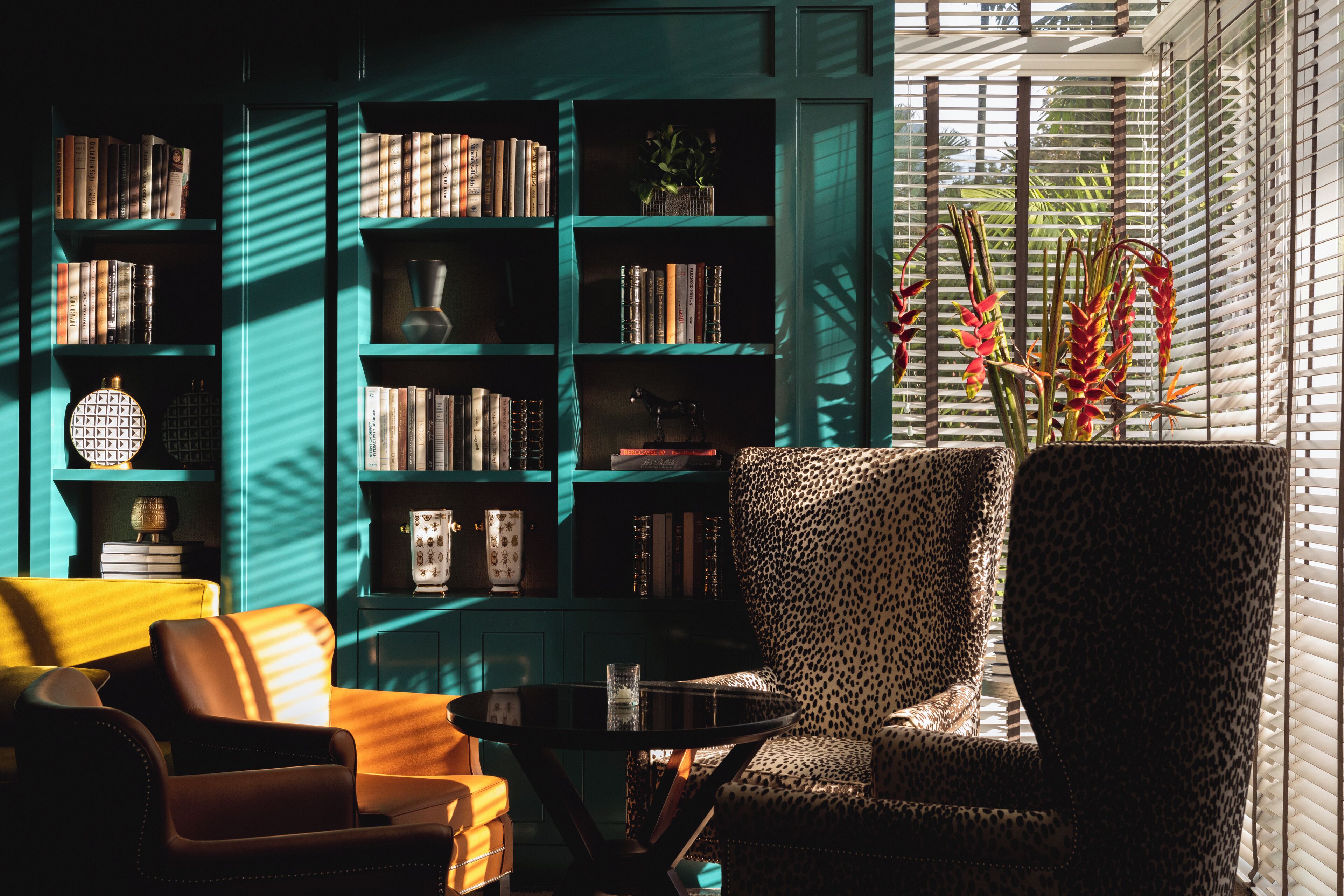 A cozy reading nook with a leopard print armchair, a small round table, and a bookshelf filled with books and decorative items.