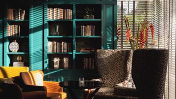 A cozy reading nook with a leopard print armchair, a small round table, and a bookshelf filled with books and decorative items.