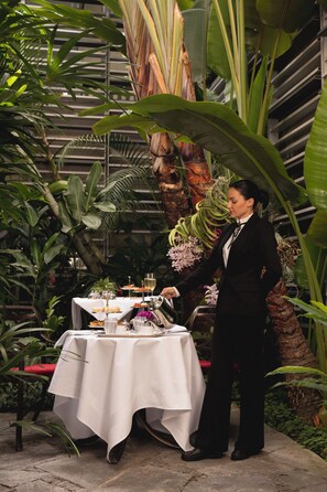 Une table dressée avec de la nourriture et des boissons, entourée d’une végétation tropicale luxuriante.