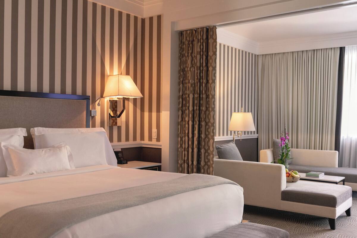 Une chambre d’hôtel avec un grand lit, un canapé, un bureau et une lampe.