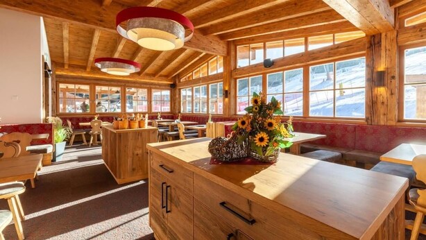 A wooden interior with a central island, benches, and large windows.