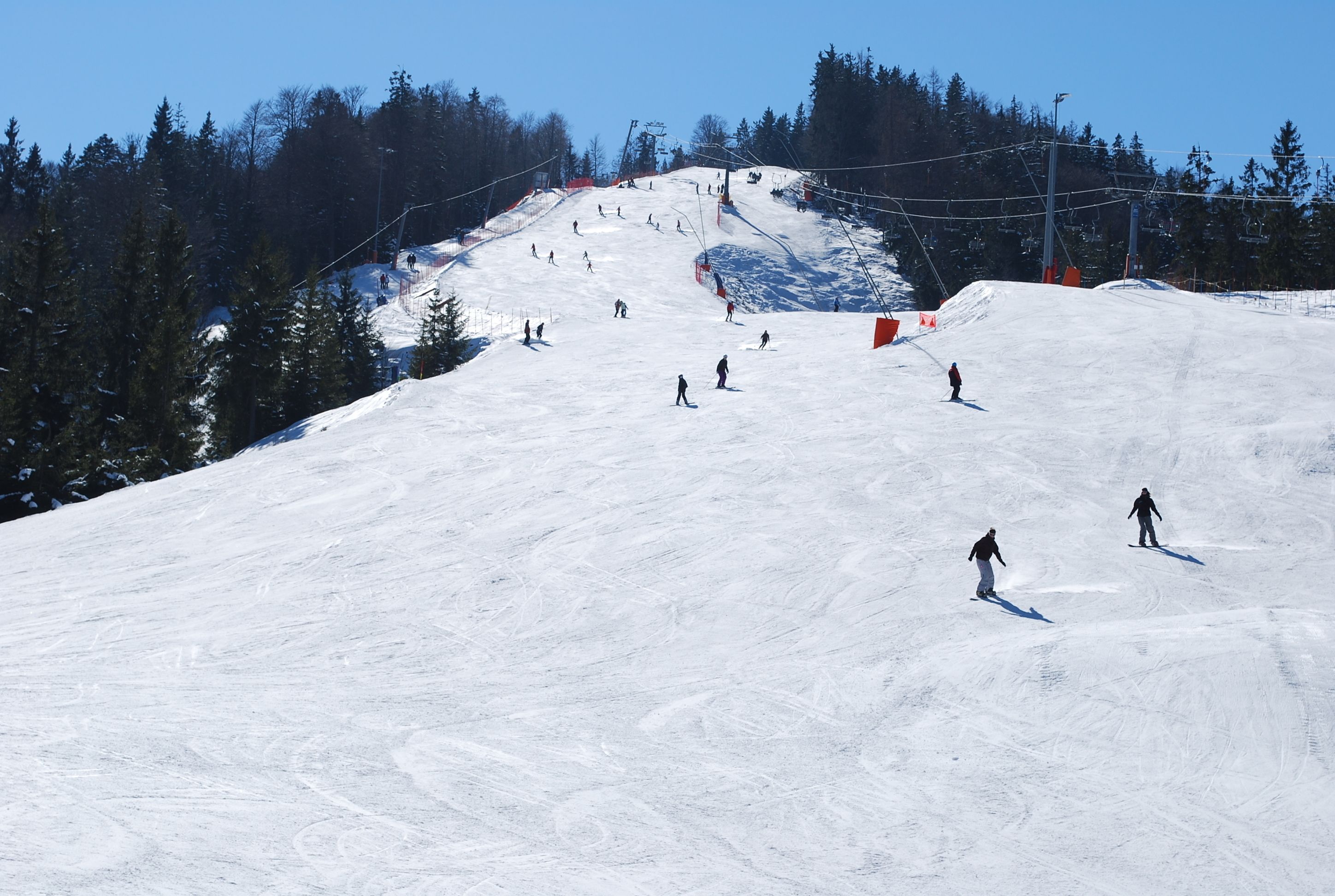 A snowy ski slope with skiers and a ski lift.