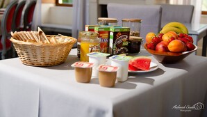 Une table de petit-déjeuner avec du pain, des fruits, du yaourt et du jus.