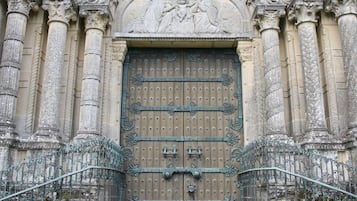 A grand entrance with a large, ornate wooden door, flanked by columns and intricate carvings, leading to a staircase.