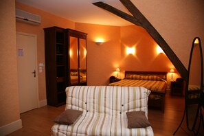 Une chambre avec un canapé à rayures, deux lits, une armoire et des lampes fixées au mur.