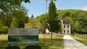 Une enseigne indiquant l’hôtel Domaine de Chantemerle, avec un chemin menant à un bâtiment entouré d’arbres.
